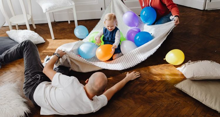 Happy family playing with colorful balloons indoors, enjoying a fun and joyful moment.
