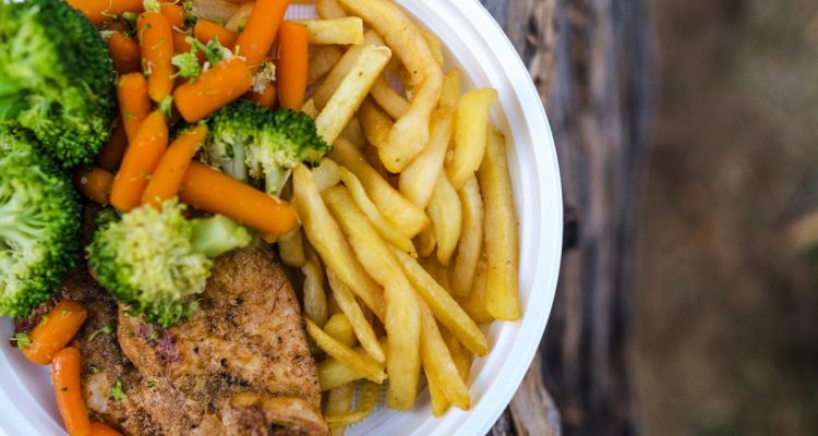 Delicious chicken dinner with broccoli, carrots, and fries on a plate.